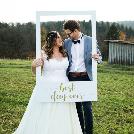Brautpaar schaut sich an im Fotorahmen "Best Day ever" Hochzeit
